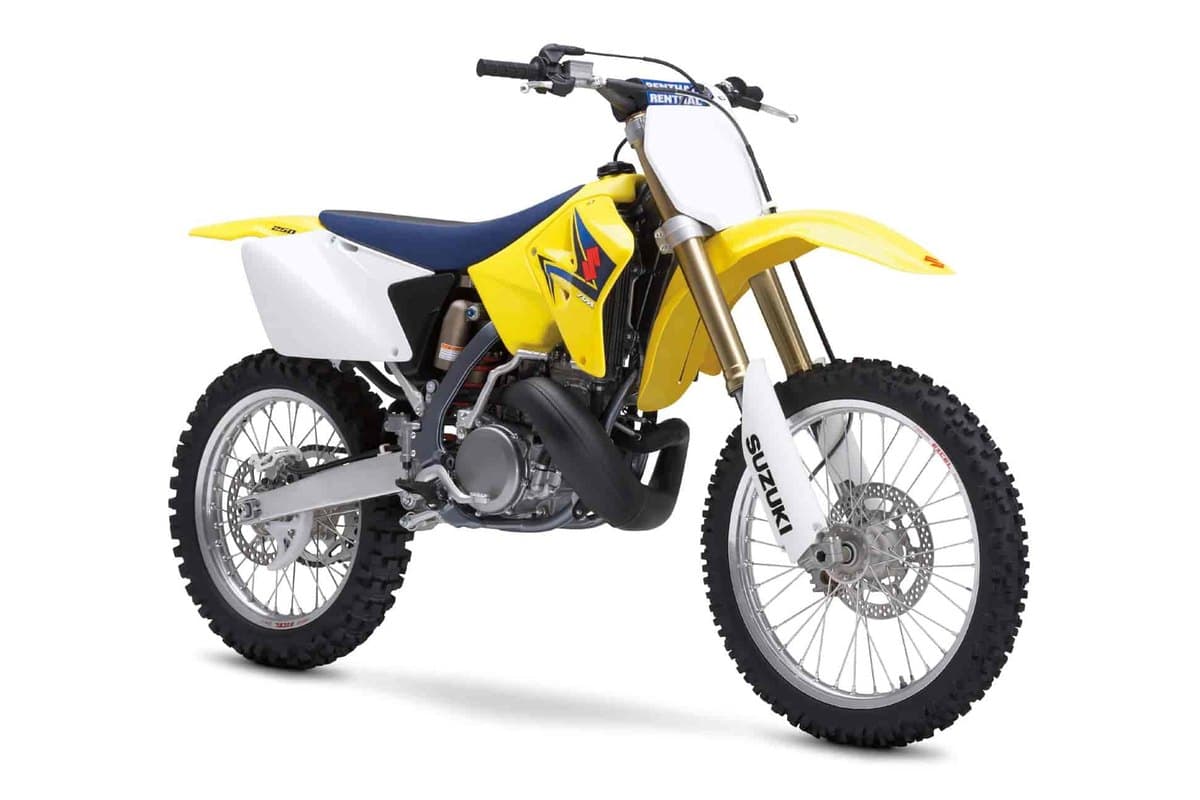 2008 Suzuki RM250 two-stroke motocross bike in yellow with white number plates and blue seat, front three-quarter studio profile showing gold forks and spoked wheels