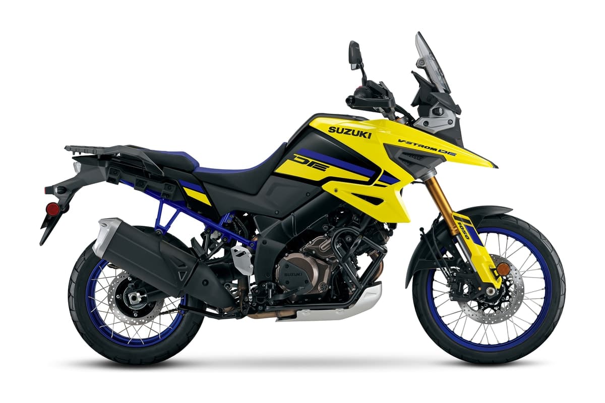 2027 Suzuki V-Strom 1050DE in Champion Yellow No. 2 and Glass Sparkle Black, right-side studio profile showing the blue-rimmed spoked wheels, gold fork tubes and rear rack