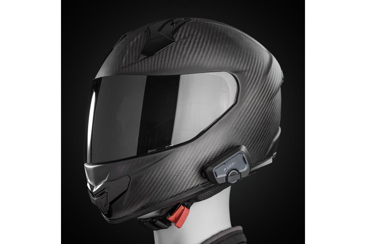 Cardo Freecom 4x mounted on the left side of a carbon full-face helmet on a mannequin