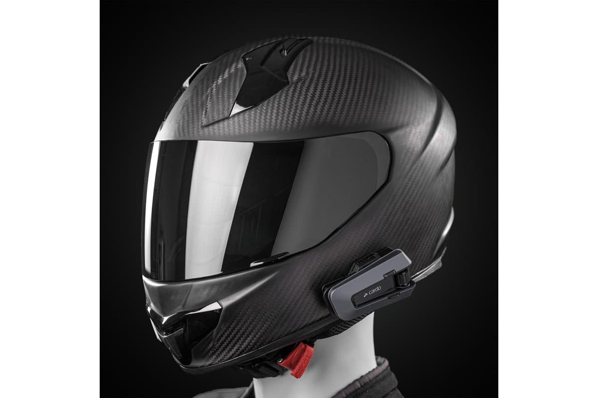 Cardo Packtalk Edge mounted on the left side of a carbon full-face helmet on a mannequin