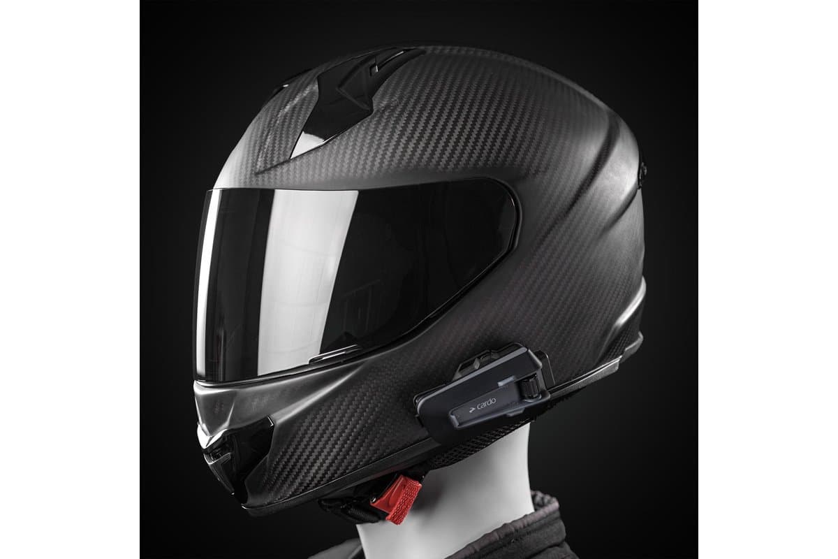 Cardo Packtalk Neo mounted on the left side of a carbon full-face helmet on a mannequin