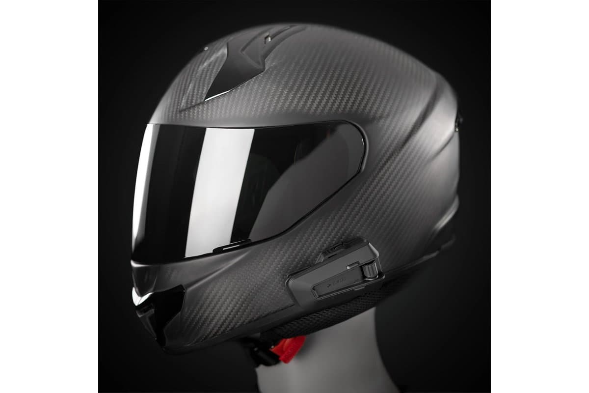 Cardo Packtalk Pro mounted on the left side of a carbon full-face helmet on a mannequin