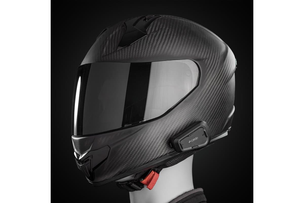 Cardo Spirit HD mounted on the left side of a carbon full-face helmet on a mannequin