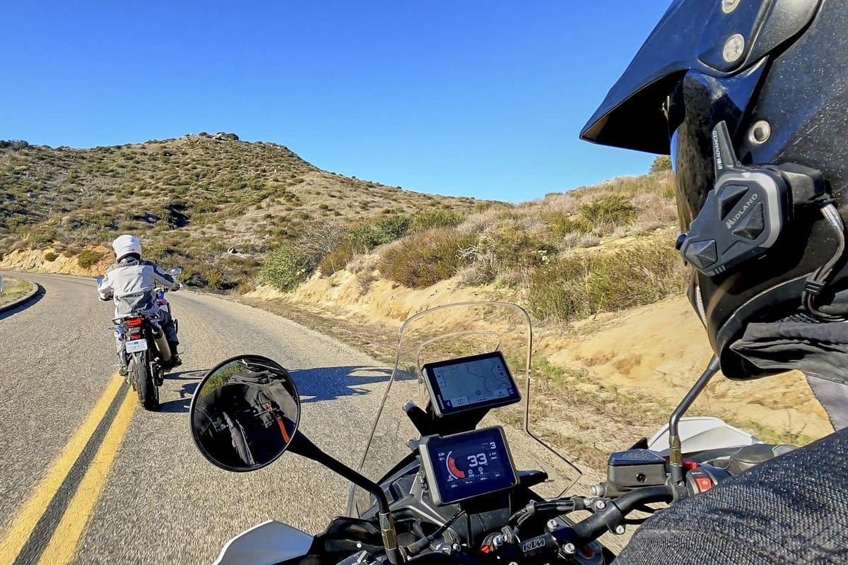Rider's view from an adventure bike on a mountain road, with the BTR1 Advanced on the side of a dual sport helmet