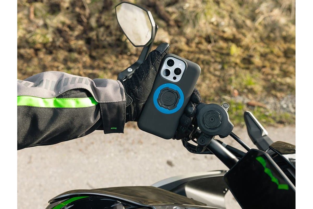 Rider in gloves attaching a phone in a Quad Lock case to a Handlebar Mount PRO with the optional dampener and charging head