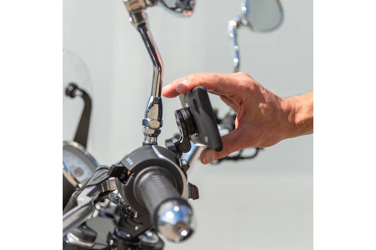 Hand attaching a phone to a Clutch Mount Pro fitted at a cruiser's left lever clamp