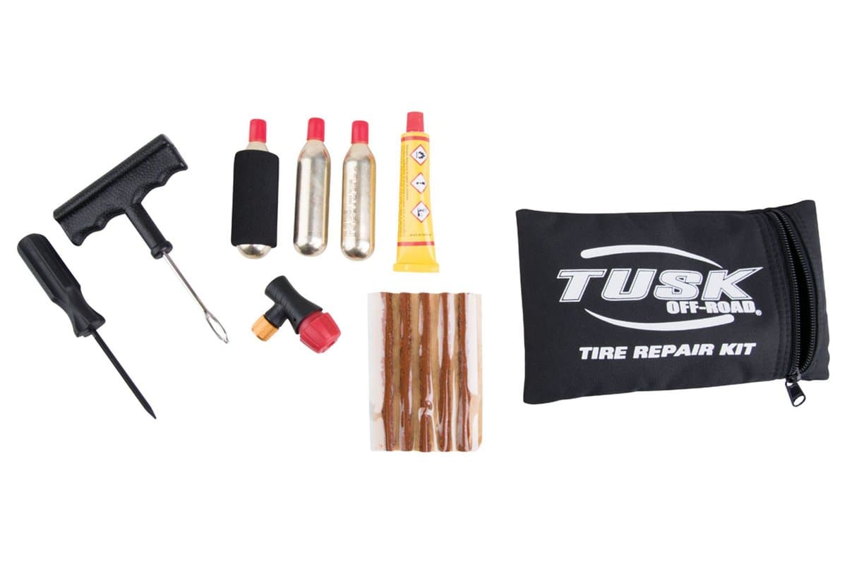 Tusk Tire Repair Kit laid out: plug tools, plugs, glue, CO2 inflator and cartridges beside its pouch