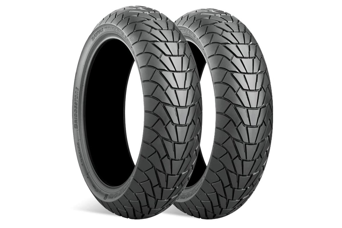 Bridgestone Battlax Adventurecross Scrambler AX41S: front and rear tire leaned together in a three-quarter view, the tight chevron scrambler tread clearly visible, on white