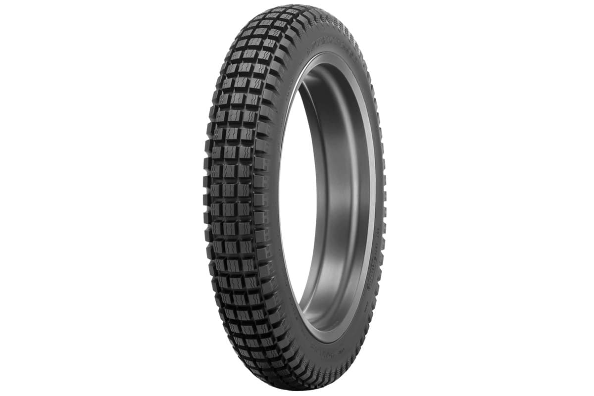 Dunlop K950: the rear tire on a bare silver rim, three-quarter view on white, fine square trials blocks