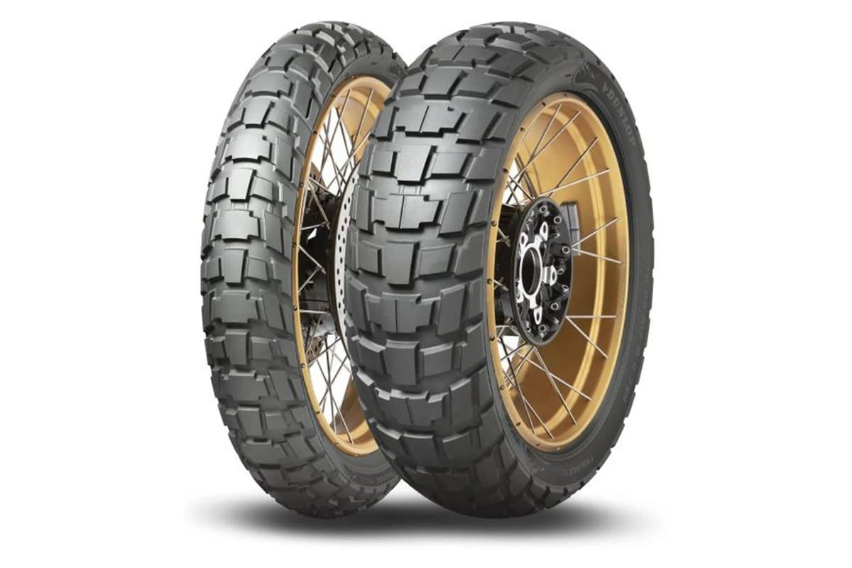 Dunlop Trailmax Raid: front and rear pair mounted on gold spoked wheels, the front with its brake disc at left and the wider rear with its sprocket carrier at right, on white