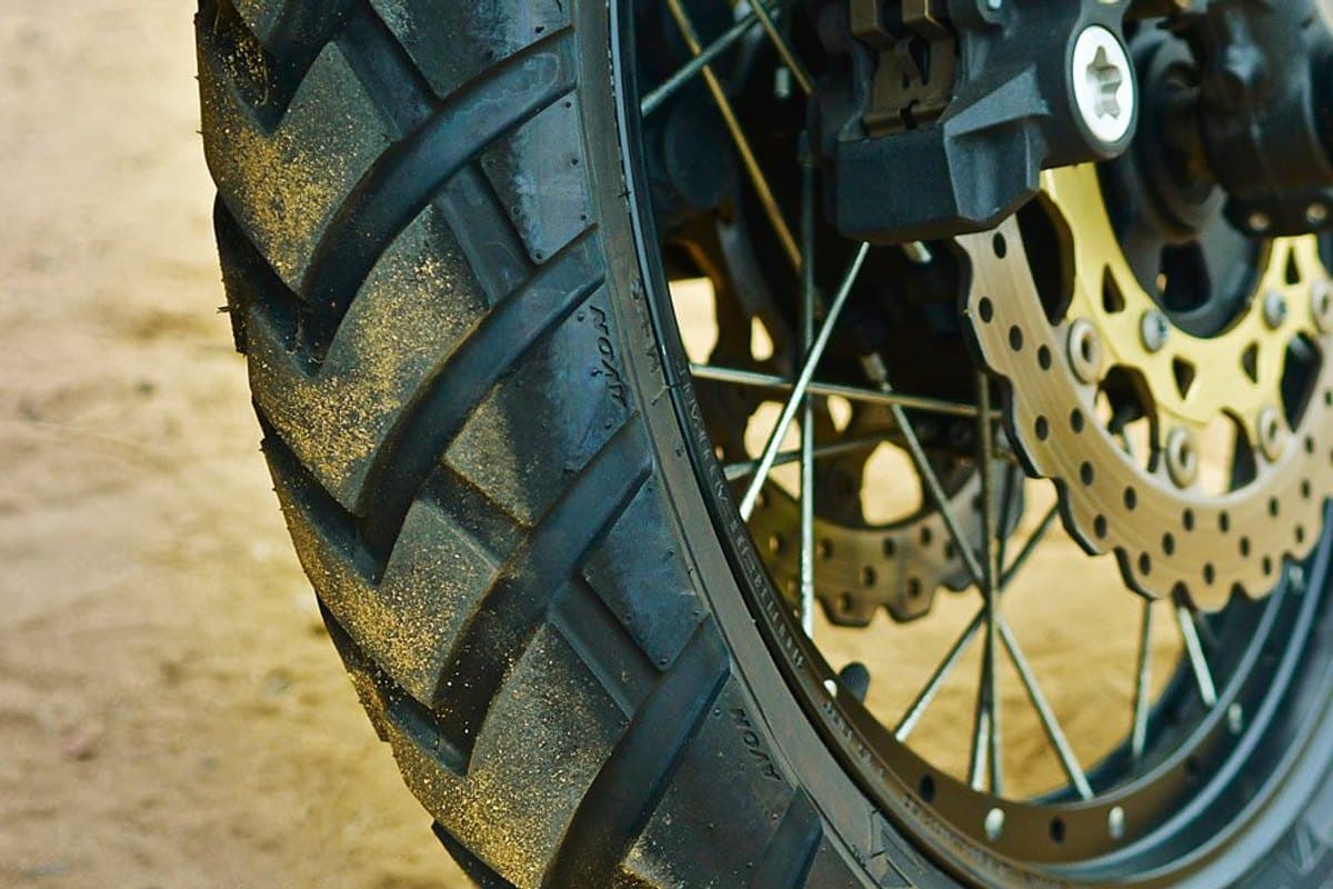 Avon TrekRider AV84/AV85: a dusty mounted tire in close-up, the shoulder blocks and brake disc in frame, shot on sand