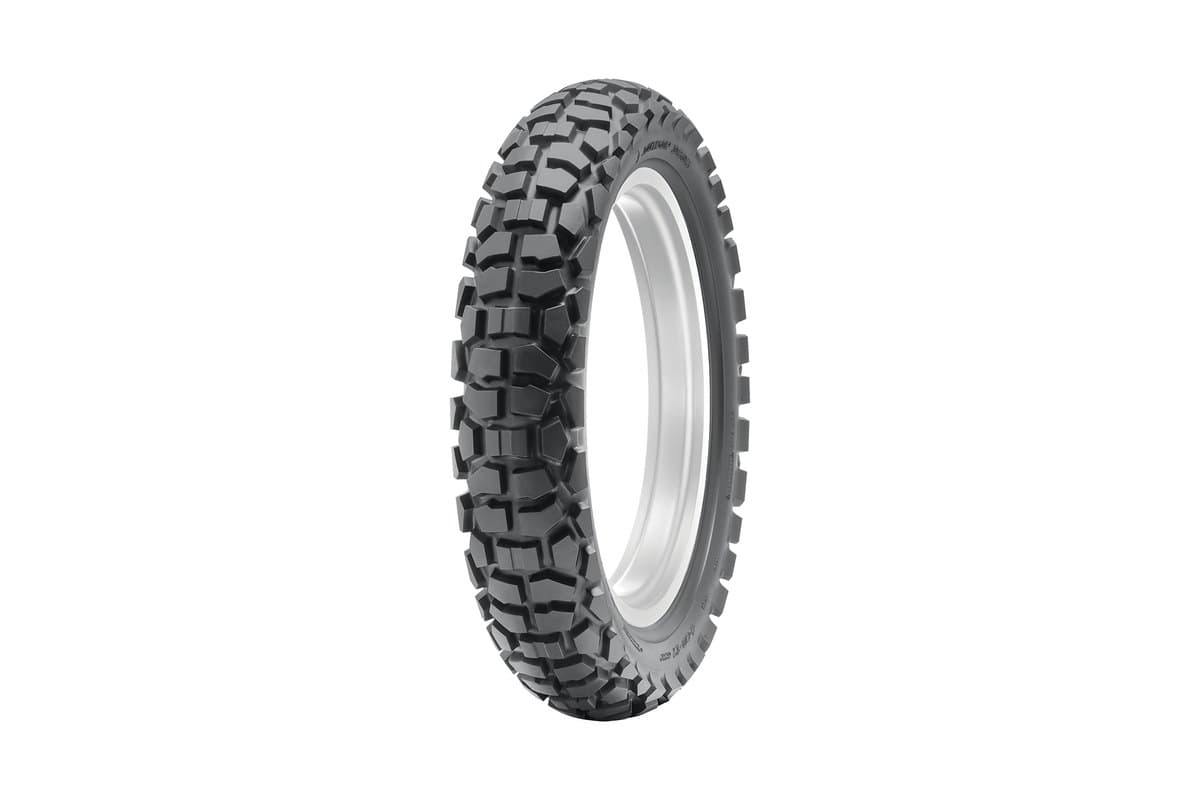 Dunlop D605: rear tire on a bare rim, same angle, visibly wider with larger blocks