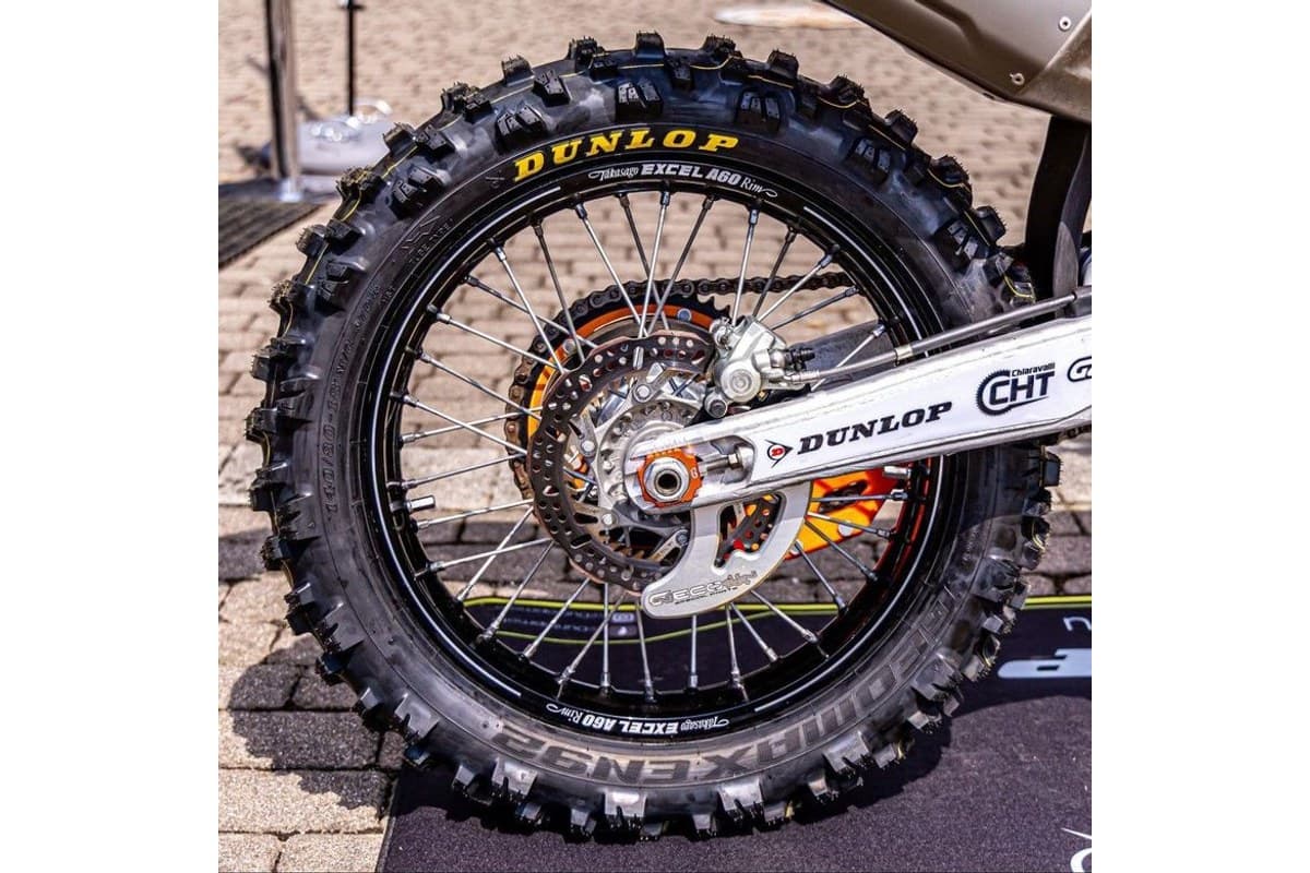 Dunlop Geomax EN92: 140/80-18 rear mounted on a black spoked wheel on a dirt bike, GEOMAX EN92 moulded into the sidewall, parked on paving