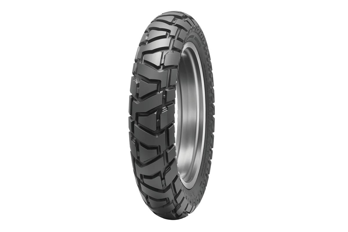 Dunlop Trailmax Mission: rear tire on a bare rim, same angle, visibly wider with larger blocks than the front
