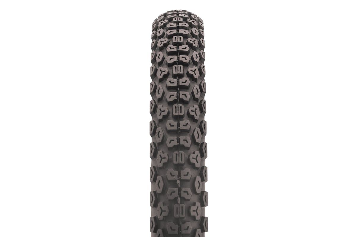 Kenda K270 Dual Sport: straight-down tread macro, a strip of the crown filling the frame so the stud and arrow block shapes are fully legible