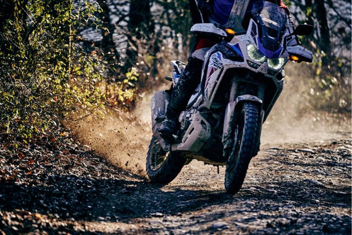 Metzeler Karoo 4: an adventure bike under power on a rocky trail throwing dirt off the rear, both tires in frame
