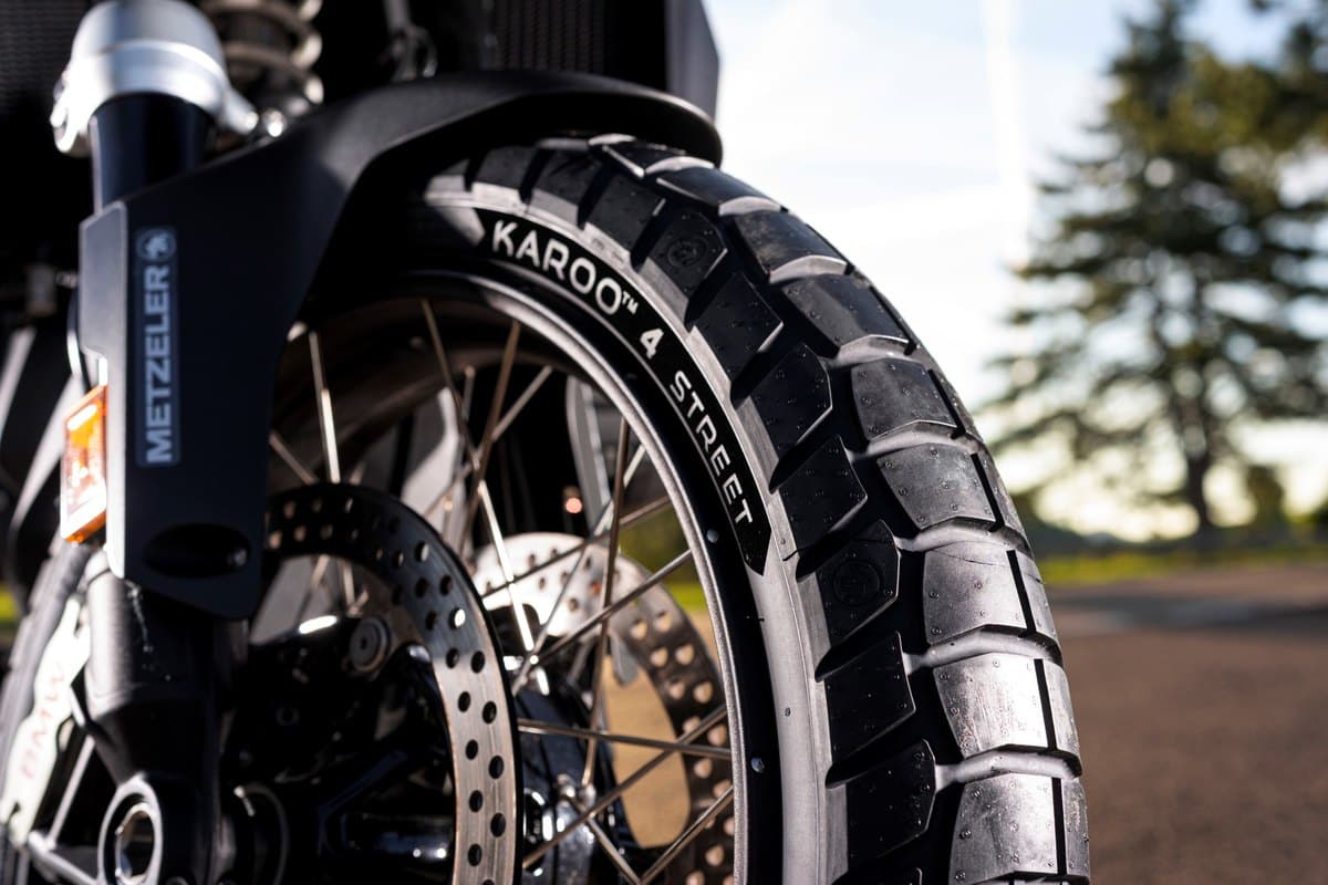 Metzeler Karoo 4 Street: close-up of the front tire fitted to a bike in low sun, fork leg, brake disc and sidewall lettering all sharp