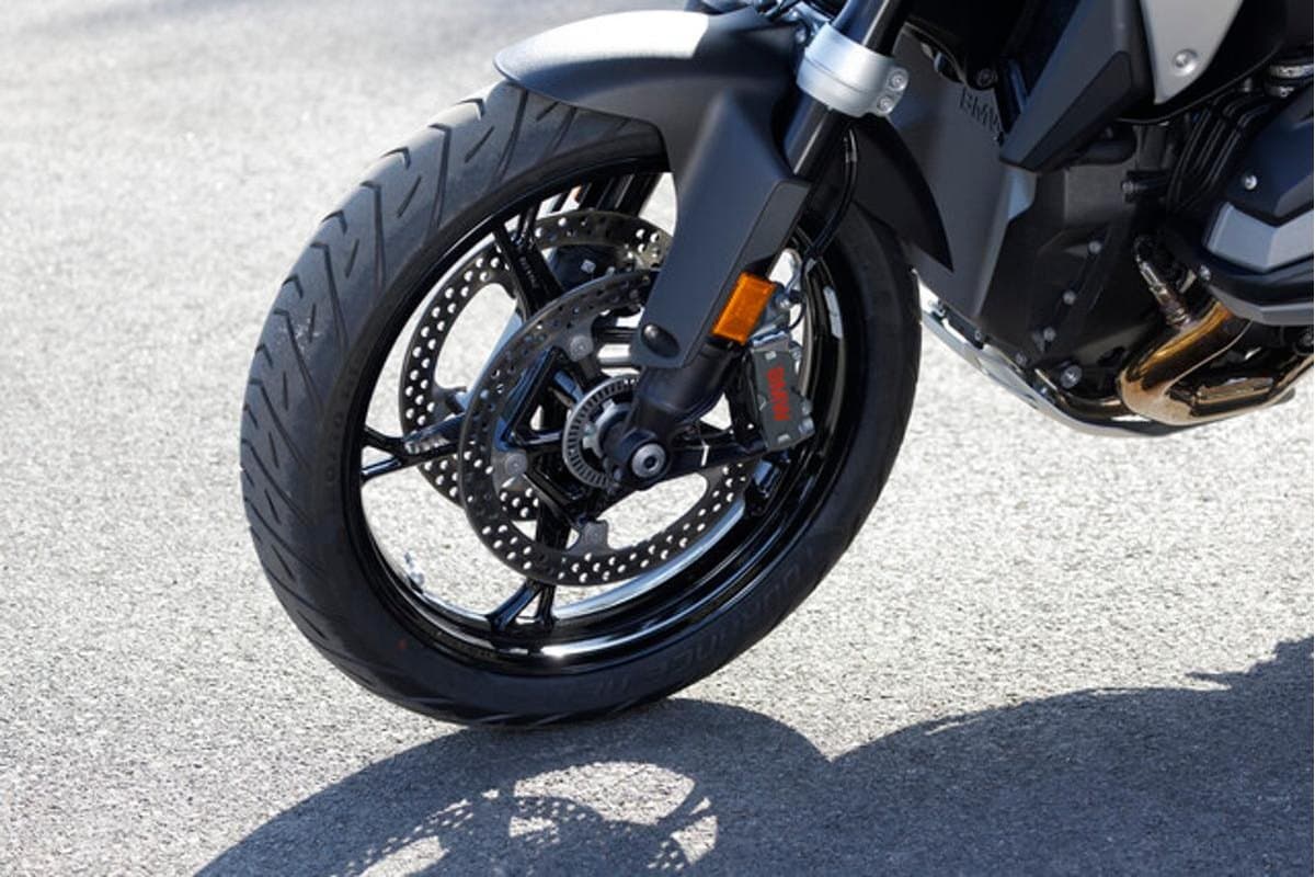 Metzeler Tourance Next 2: the front wheel of a large adventure bike on tarmac at a low three-quarter angle, cast wheel with twin discs and radial caliper