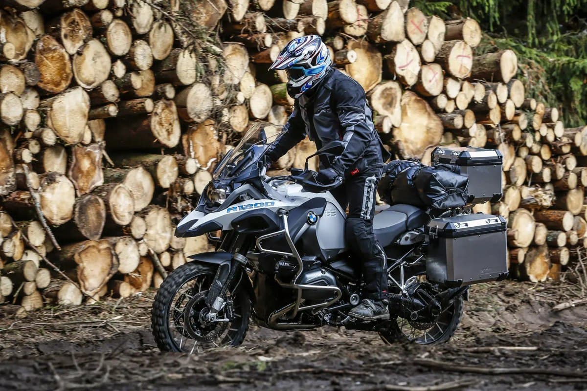 Michelin Anakee Wild: a loaded adventure bike riding through a muddy logging yard, the knobby front tire clearly visible