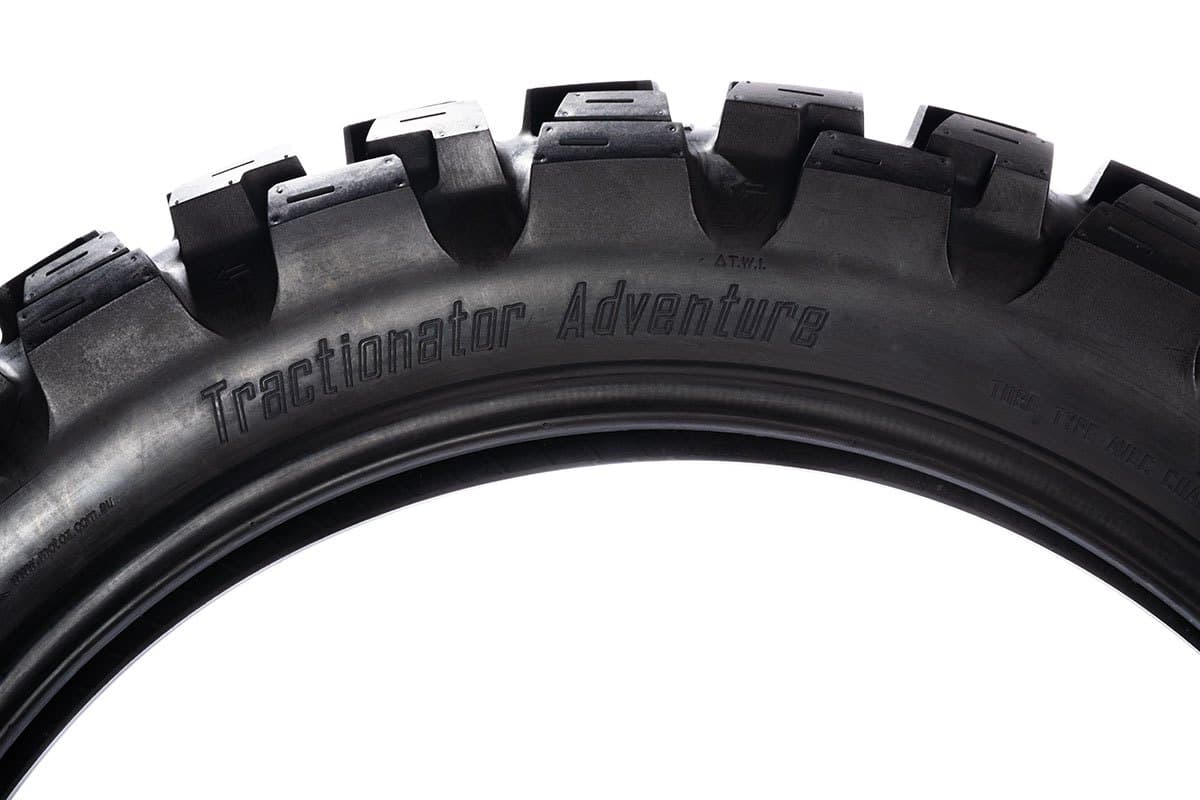 Motoz Tractionator Adventure: the upper arc of the tire side on so the knobs read as a silhouette, with the model name moulded in the sidewall below