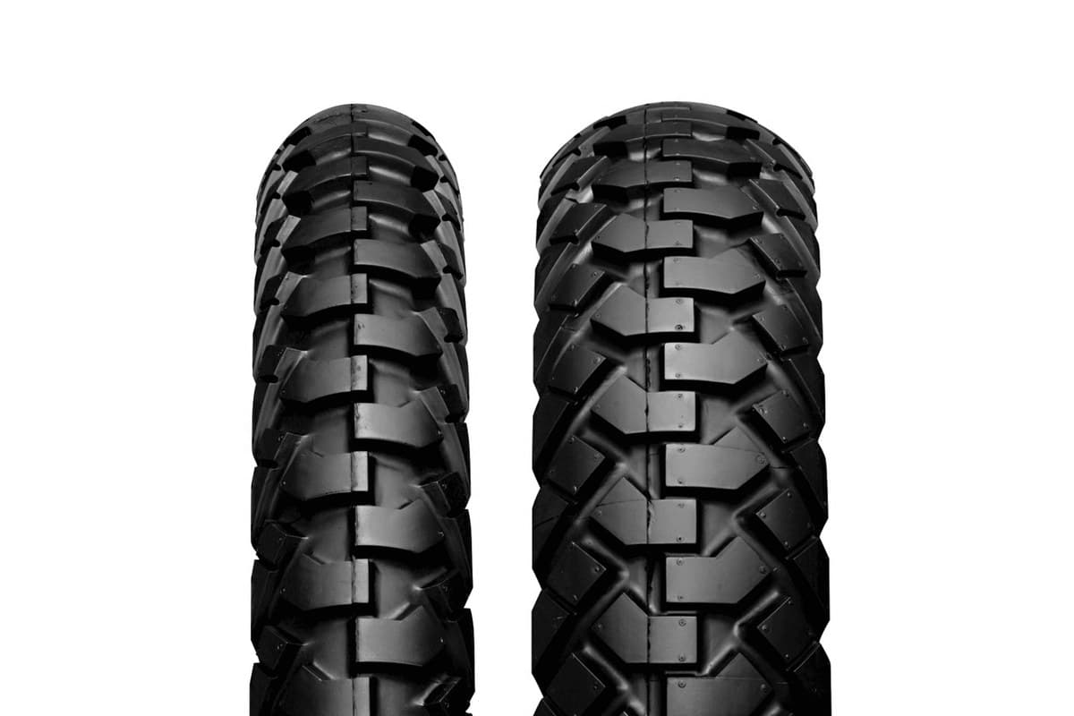 IRC GP-110: the front at left and the wider rear at right, tread faces head-on, stepped chevron blocks down the centre, on white