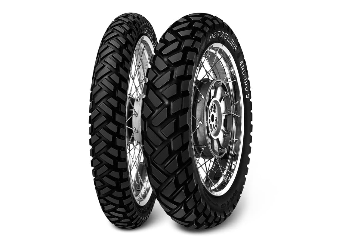 Metzeler Enduro 3 Sahara: front and rear pair on silver spoked wheels, three-quarter view, METZELER and ENDURO 3 moulded on the rear sidewall, on white