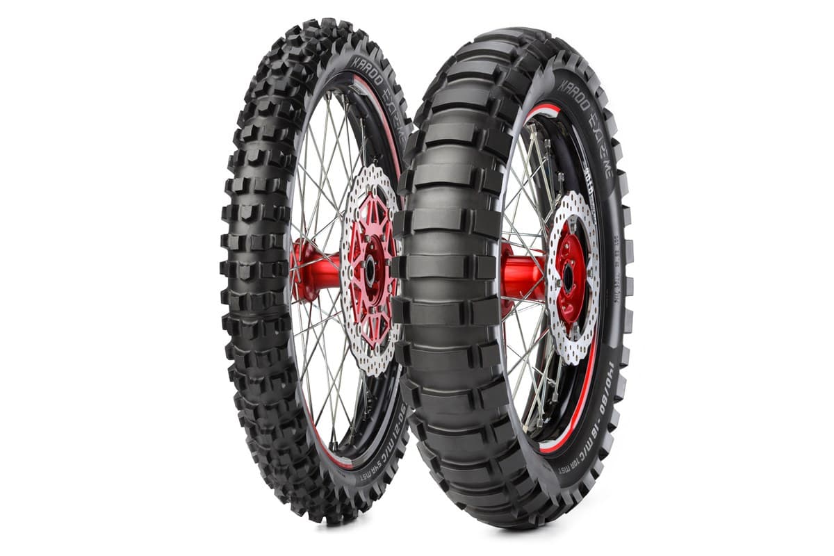 Metzeler Karoo Extreme: front and rear pair on black spoked wheels with red hubs and wave discs, three-quarter view, the model and the sizes 90/90-21 and 140/80-18 moulded on the sidewalls, on white