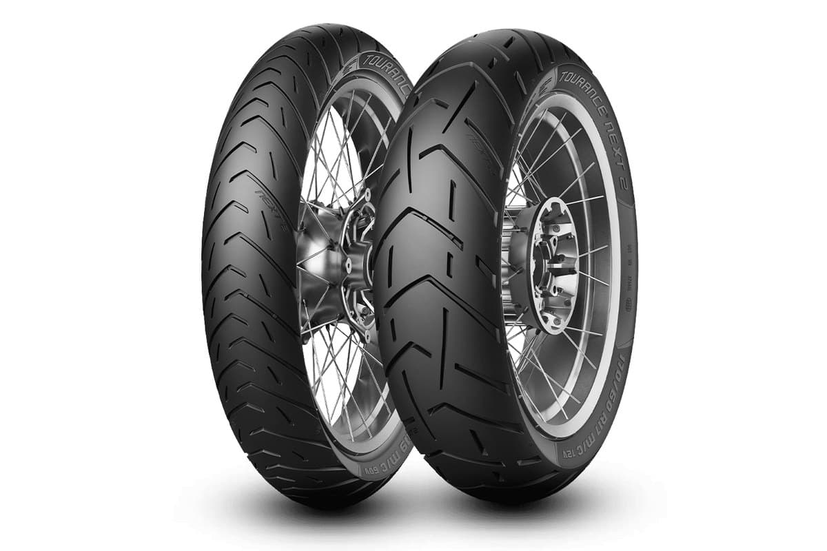 Metzeler Tourance Next 2: front and rear pair on silver spoked wheels, three-quarter view, with the model and size readable on the rear sidewall