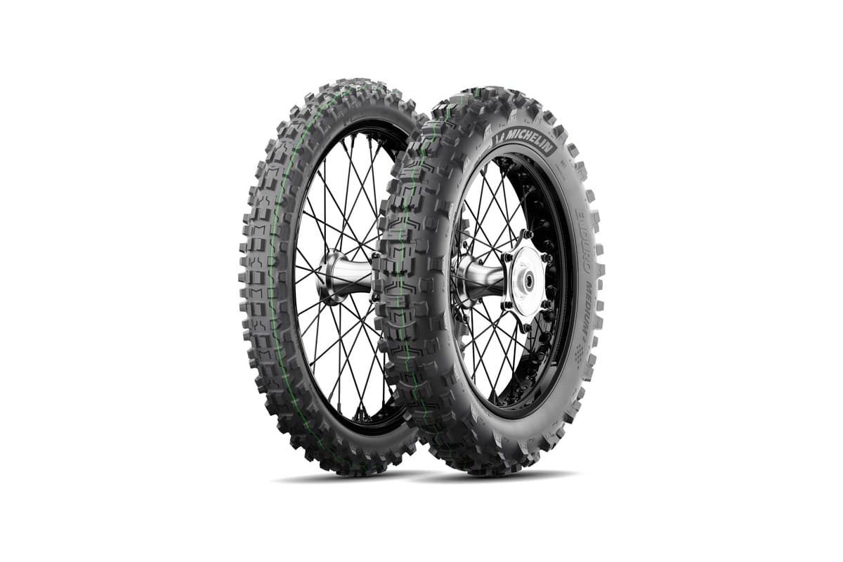 Michelin Enduro Medium 2: front and rear pair on black spoked dirt wheels, three-quarter view, a green stripe running round each tread and MICHELIN on the rear sidewall, on white