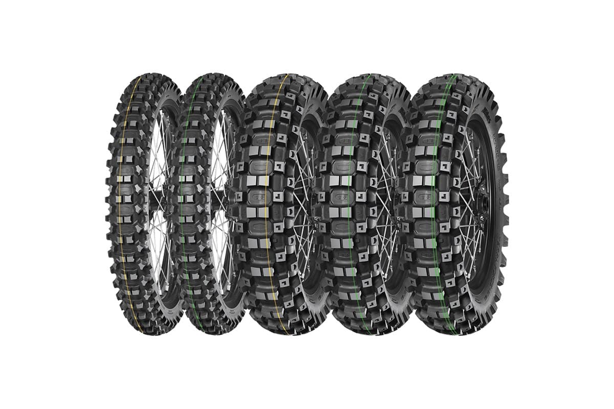 Mitas Terra Force-EX MH: five tires in a row on spoked wheels, two fronts with yellow and green tread stripes at left and three rears with yellow, green and double green stripes, on white