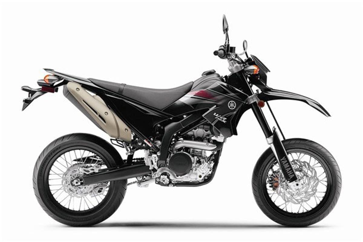 2011 Yamaha WR250X supermoto in black with red accents, right-side studio profile showing spoked wheels, tall front fender and stubby exhaust