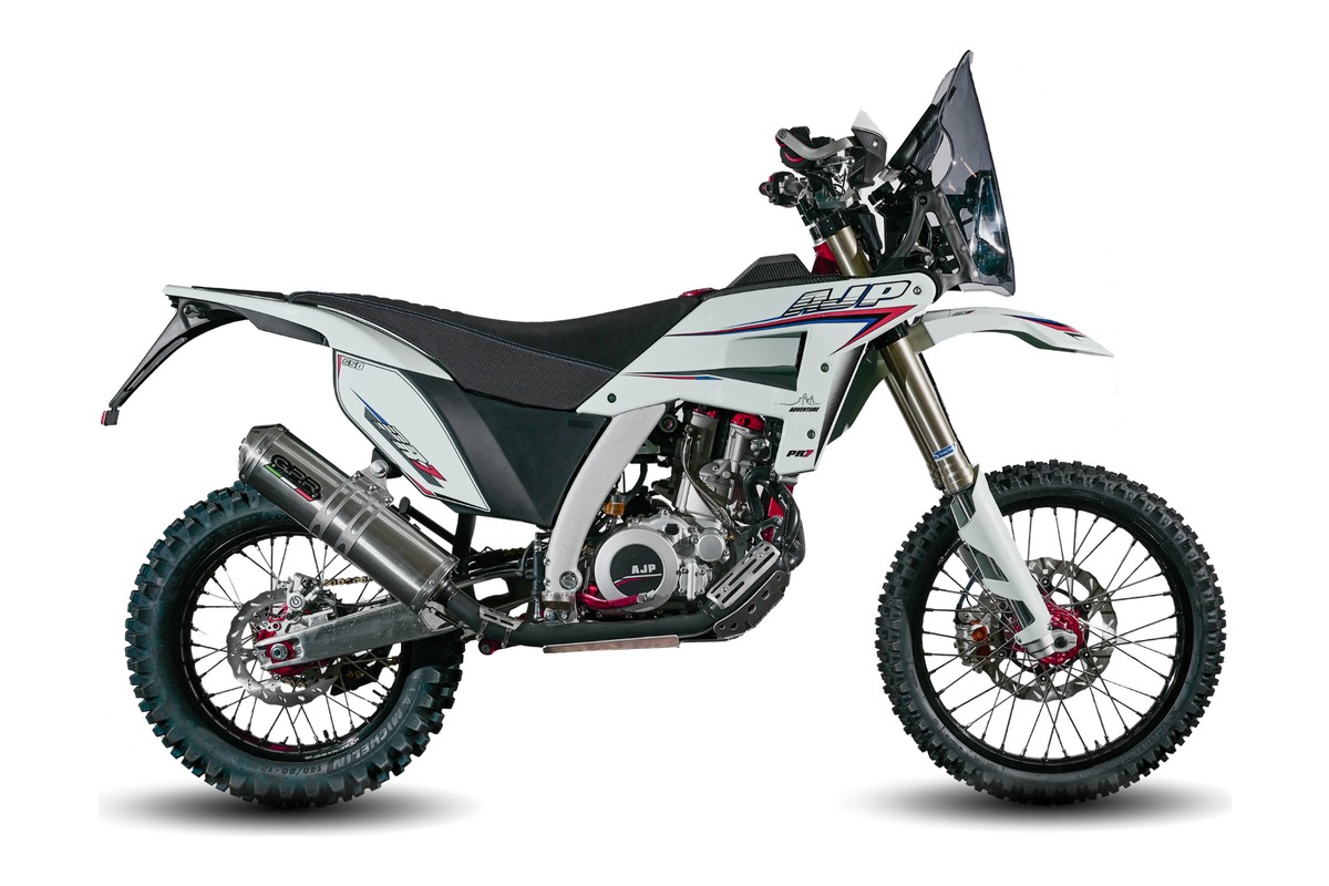 2027 AJP PR7 dual-sport motorcycle in white with red and blue accents, right-side studio profile showing spoked wheels and rally-style headlight cowl