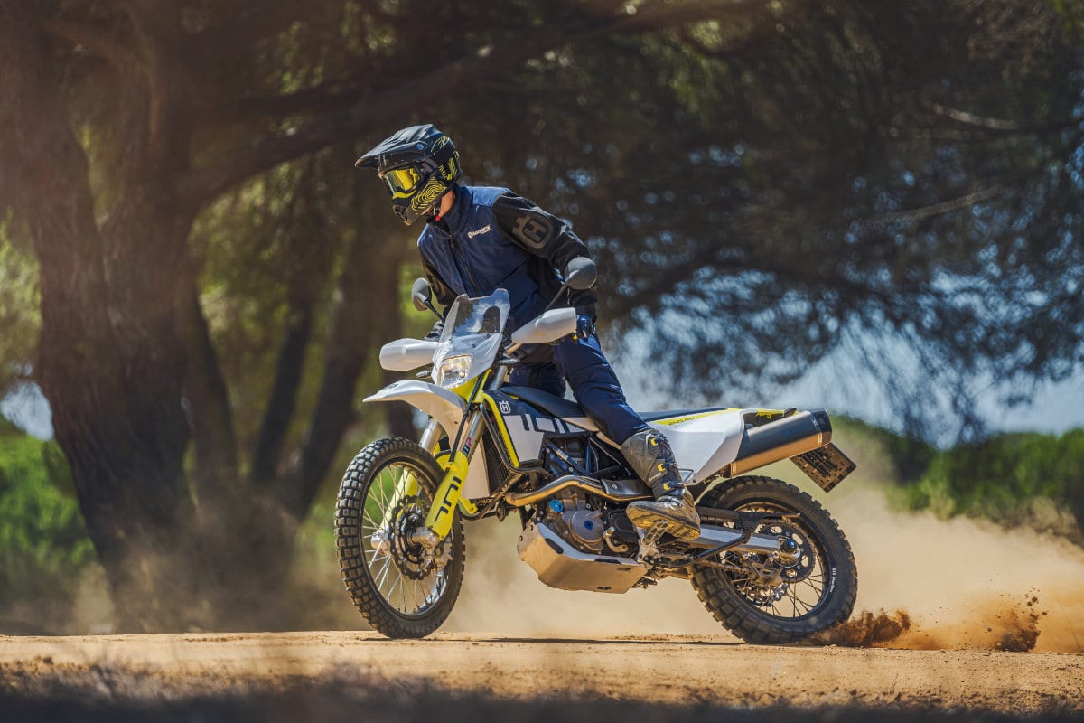 A rider sliding a Husqvarna 701 Enduro through sandy dirt
