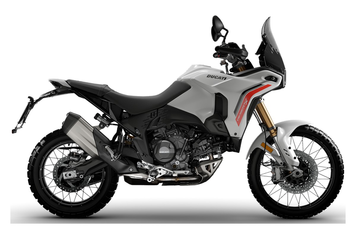 2026 Ducati DesertX V2 adventure bike in white with red accents, left-side studio profile showing the spoked wheels, gold forks and high front fender