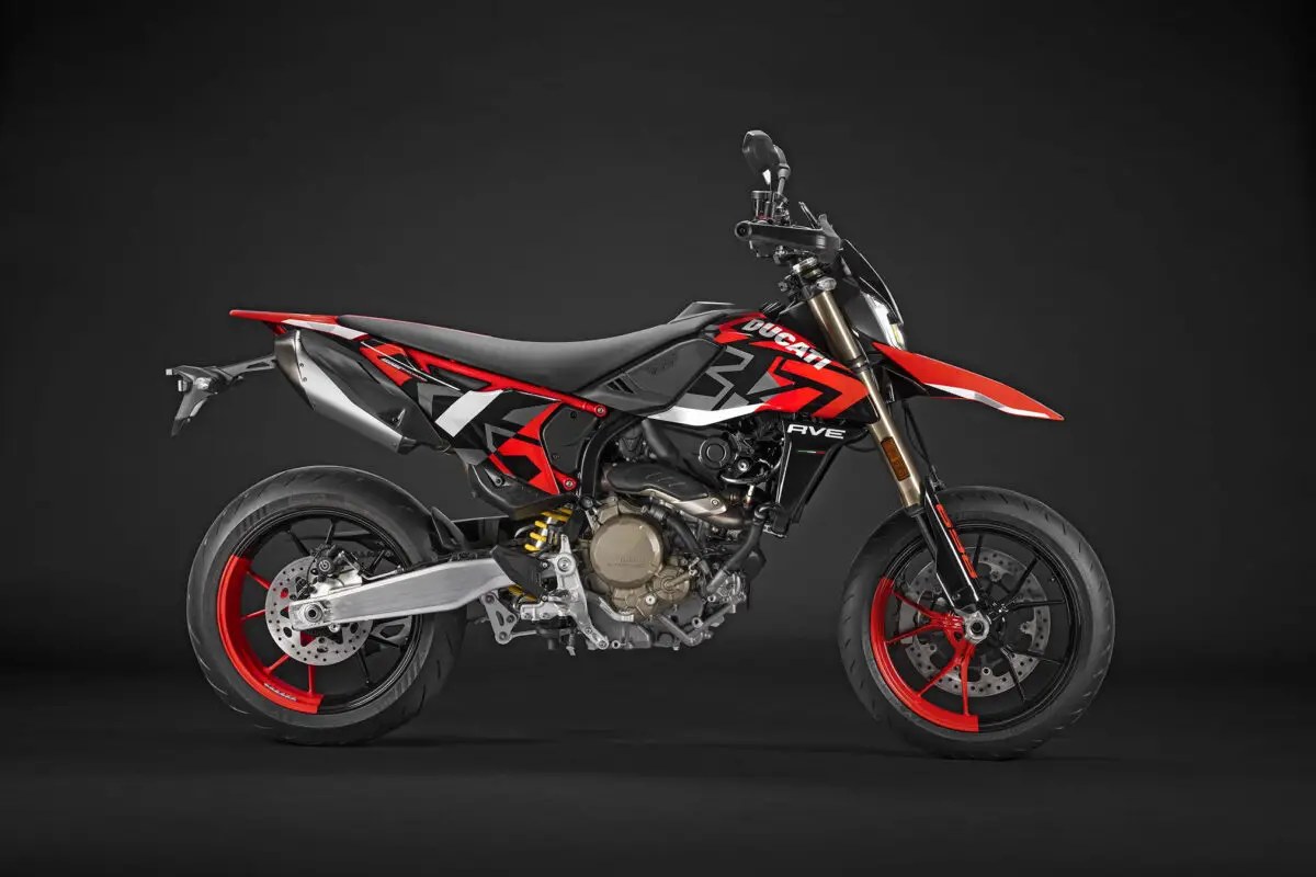 2026 Ducati Hypermotard 698 Mono RVE in black and red livery, left-side studio profile showing the underslung twin exhaust and red-spoked wheels