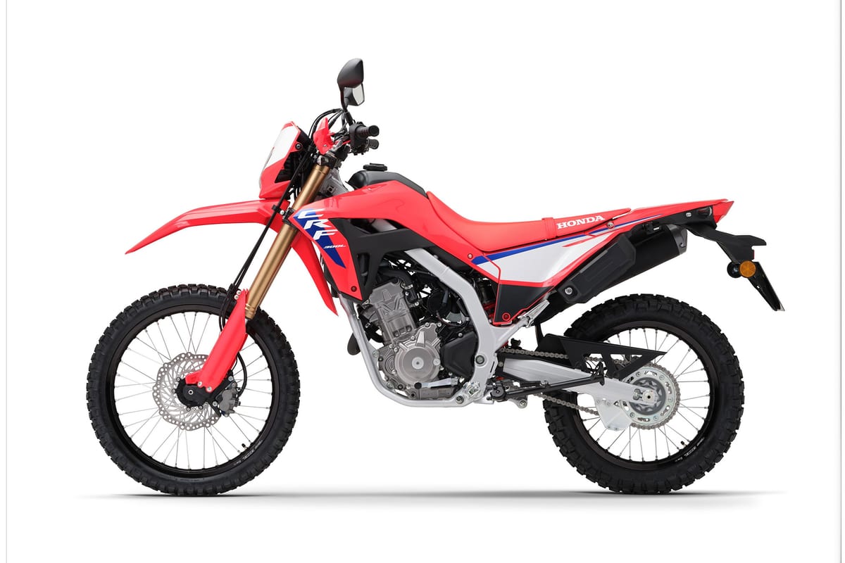 2026 Honda CRF300L in red, left-side studio profile showing the long-travel gold fork and knobby dual-sport tires