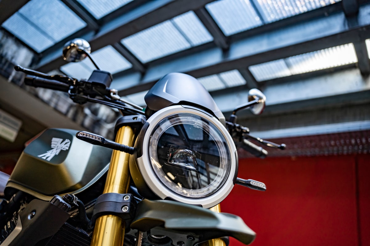 Close-up of the Moto Morini Seiemmezzo SCR front end in olive green, showing the round LED headlight, fly screen and gold inverted fork