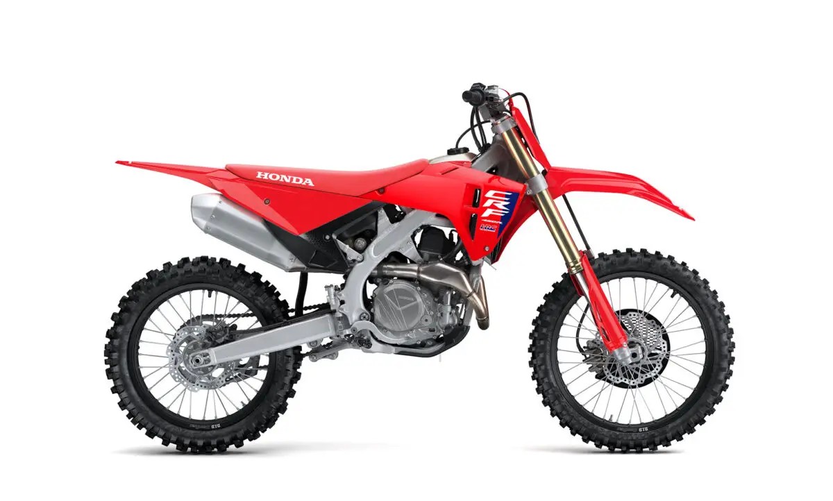 2027 Honda CRF450R motocross bike in red and white, right-side studio profile showing gold-anodized forks, silver exhaust and spoked wheels
