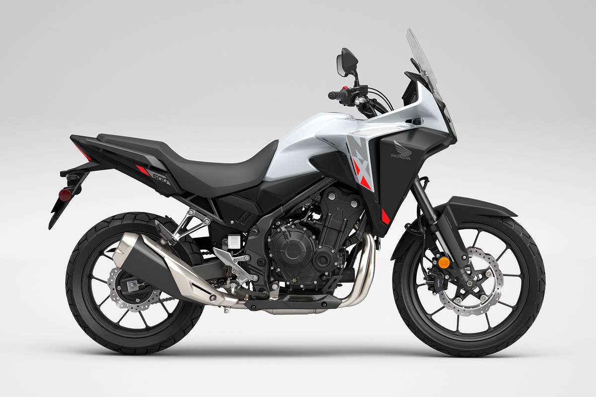 2026 Honda NX500 adventure motorcycle in white and black, right-side studio profile showing the tall windscreen, twin-spar bodywork and knobby dual-sport tires