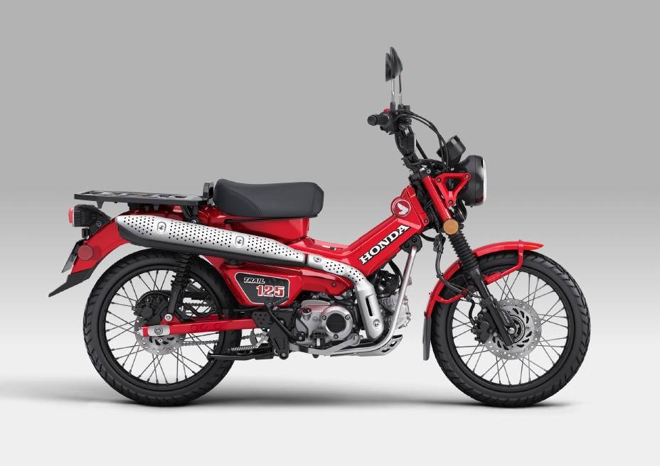 2026 Honda Trail125 in red, right-side studio profile showing the rear cargo rack, spoked wheels and silver step-through frame beam