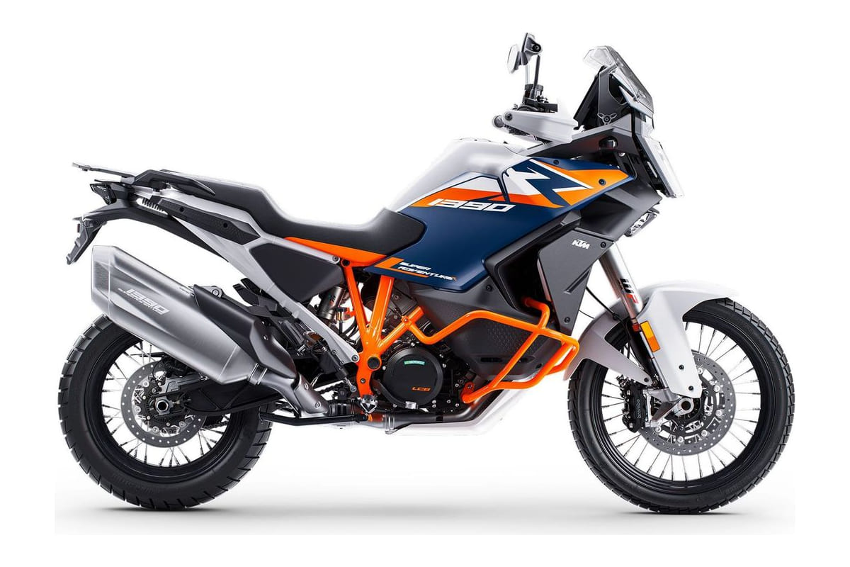 2026 KTM 1390 Super Adventure R in white, orange and blue, left-side studio profile showing spoked wheels, orange trellis frame and tall windscreen