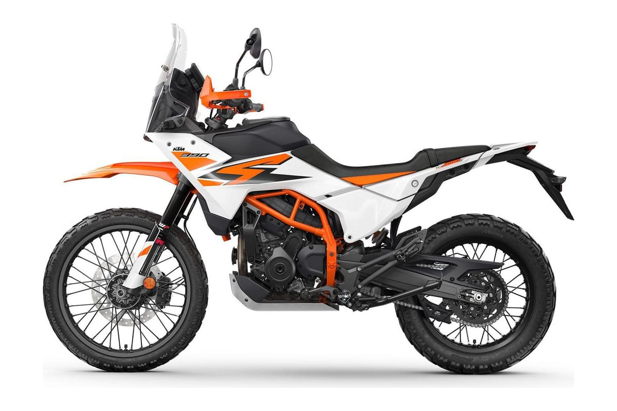 2026 KTM 390 Adventure R in white and orange, left-side studio profile showing the spoked wheels, tall windscreen and trellis subframe
