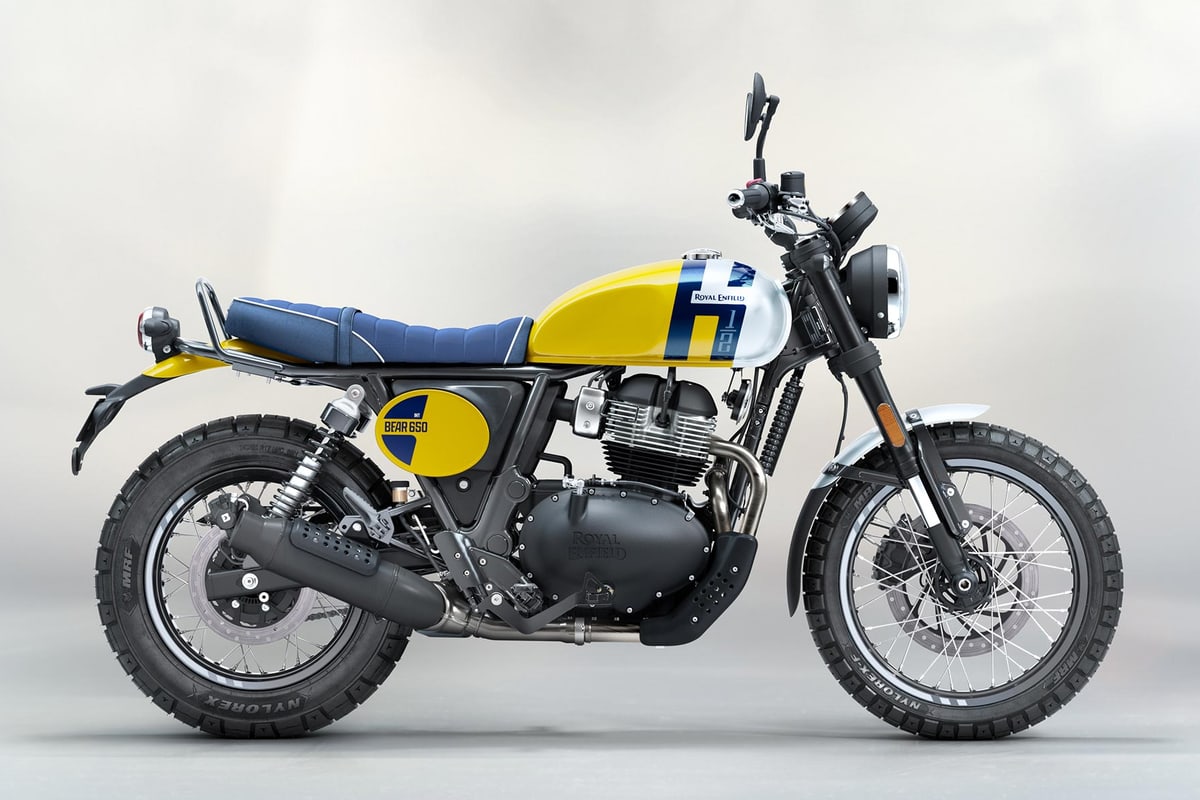 2026 Royal Enfield Bear 650 scrambler in Wild Honey yellow and blue, left-side studio profile showing the bench seat, twin shocks, spoked wheels and block-pattern MRF tyres