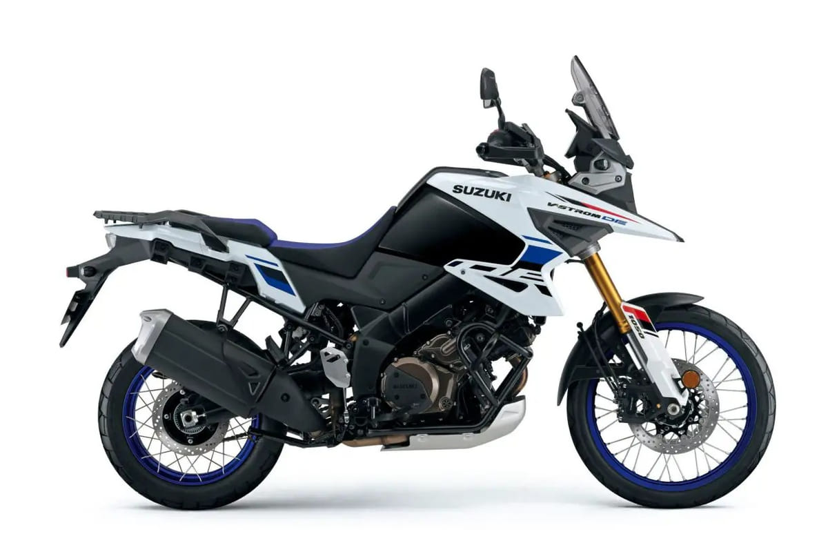 2026 Suzuki V-Strom 1050DE adventure motorcycle in white and blue, right-side studio profile showing spoked wheels, gold forks and dual exhaust