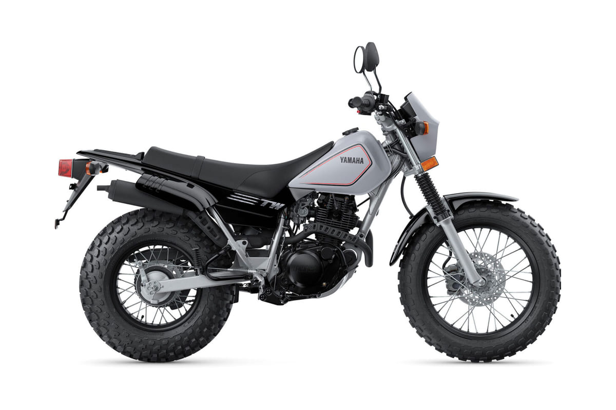 2027 Yamaha TW200 dual-sport in silver with black frame, right-side studio profile showing its trademark oversized balloon tires and dual shocks